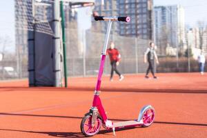 A small kid's scooter stands on the sidewalk photo