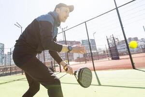 hombre jugando padel en un verde césped padel Corte interior detrás el red foto