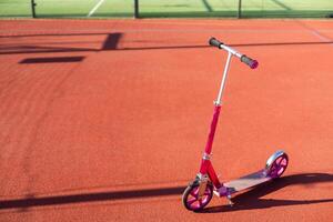 un pequeño niño scooter soportes en el acera foto