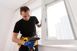 Handsome young man installing bay window in a new house construction site photo