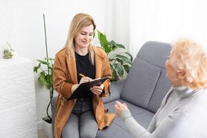 Depressed senior woman talking with female psychologist photo