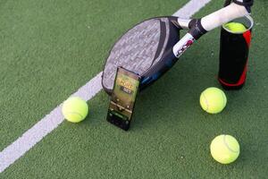 High angle view of mobile phone with tennis equipment on court background photo