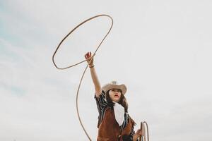 pretty Chinese cowgirl throwing the lasso in a horse paddock photo