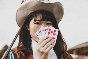 Portrait of a beautiful Chinese female cowgirl playing with poker cards photo