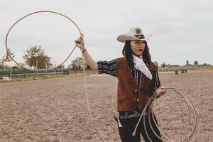 pretty Chinese cowgirl throwing the lasso in a horse paddock photo