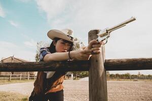 Portrait of a beautiful Chinese female cowgirl shooting with a weapon photo