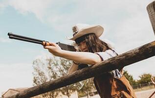 Portrait of a beautiful Chinese female cowgirl shooting with a weapon photo