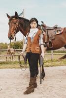 cute chinese cowgirl while taking care of her horse photo