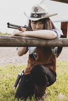 Portrait of a beautiful Chinese female cowgirl shooting with a weapon photo