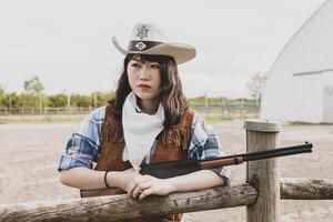 Portrait of a beautiful Chinese female cowgirl shooting with a weapon photo