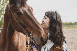 cute chinese cowgirl while taking care of her horse photo