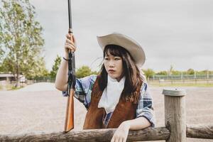 Portrait of a beautiful Chinese female cowgirl shooting with a weapon photo