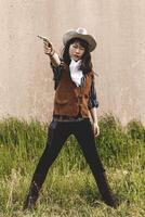 Portrait of a beautiful Chinese female cowgirl shooting with a gun photo