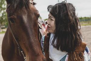 cute chinese cowgirl while taking care of her horse photo