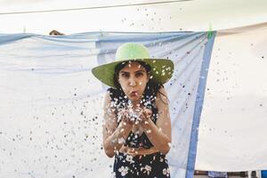 pretty woman with colorful straw hat blowing confetti photo