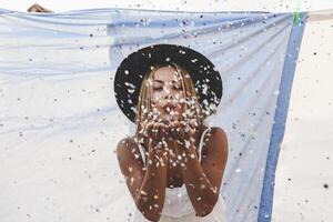 pretty woman with colorful straw hat blowing confetti photo