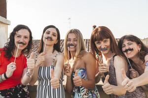 group of female friends having fun with party accessories on the roofs photo