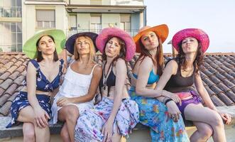 group of female friends on vacation sitting on the roofs in bikini and pareo photo