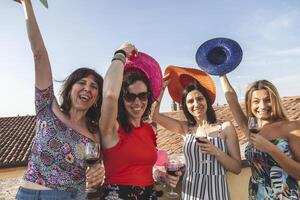 group of female friends having fun while drinking red wine on the roofs photo