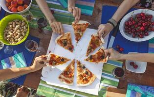 hands of girlfriends share slices of pizza from a table photo