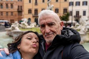 happy middle aged couple of tourist on vacation taking a selfie in front of a famous navona square in rome photo