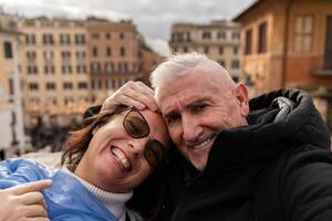 contento medio Envejecido Pareja de turistas en vacaciones tomando un selfie en frente de el famoso trinita dei Monti escalera en Roma foto