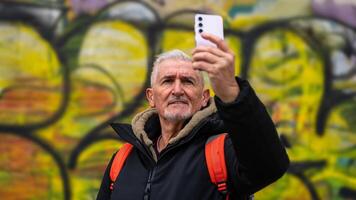 happy middle aged man on vacation taking a selfie in front of defocused graffiti in rome photo