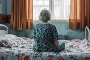 AI generated Lonely senior woman sitting on hospital bed photo