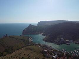 Aerial panoramic view of Balaklava landscape with boats and sea in marina bay. Crimea Sevastopol tourist attraction. Drone top view shot of port for luxury yachts, boats and sailboats. photo