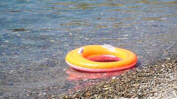 Close up rubber inflatable swim ring of a orange donut floating on the calm sea. Summer theme, nobody. Inflatable ring on beach, orange Swimming Ring Circle Floats Swim Ring Pool float Water Toys video