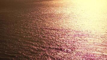zee water oppervlak. antenne visie Aan gouden zee water Bij zonsondergang. zon schittering. abstract nautische zomer oceaan natuur. vakantie, vakantie en reizen concept. niemand. langzaam beweging. weer en klimaat verandering video