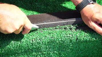 Man Cuting Artificial Grass carpet with knife. Artificial turf. Close up on hands. video