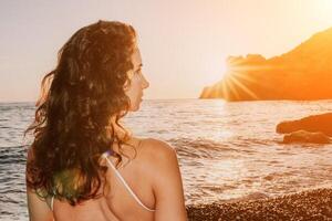 mujer mar yoga. contento mujer en blanco traje de baño y boho estilo pulseras practicando al aire libre en yoga estera por mar en puesta de sol. mujer yoga aptitud rutina. sano estilo de vida, armonía y meditación foto