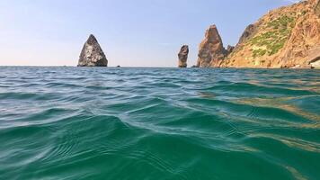 Sea water surface. Camera flies over the calm azure sea with volcanic rocky shores on background. Nobody. Holiday recreation concept. Abstract nautical summer ocean nature. Slow motion. Close up video