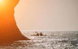 contento Pareja kayaks en un inflable kayac en el mar a puesta de sol. Pareja piragüismo en el mar cerca el isla con montañas. personas kayak en vida chaquetas navegar. espalda ver foto