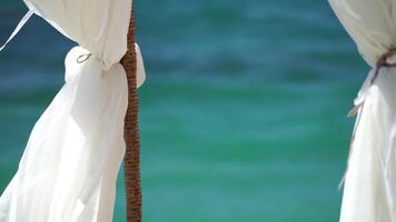 bangalôs mar. de praia salão cama com branco sedoso cortinas. salão cama com marquise às à beira-mar. de praia cadeiras e guarda-sóis. verão período de férias recorrer conceito. video