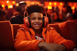 ai generado sonriente negro adolescente chico en naranja capucha y auriculares sentado en grande silla mirando a cámara, borroso bokeh antecedentes. juventud cultura, relajación, música, estilo. diversidad y estilo de vida foto