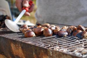 Roasted chestnuts for sale on the street in mountain Greek village. Street food. Grilled chestnuts on fire. photo