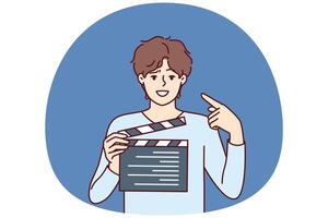 Man producer with clapboard in hands looks at screen while working on set of film or clip vector