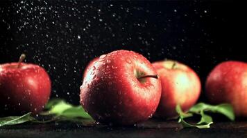 druppels van water met spatten vallen Aan de rood appels. Aan een zwart achtergrond. gefilmd is langzaam beweging 1000 kaders per seconde. video