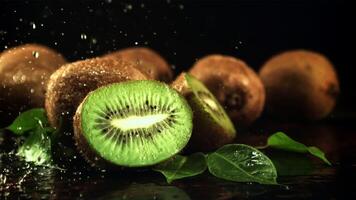Splashes of water fall on the sliced kiwi. On a black background.Filmed is slow motion 1000 frames per second. High quality FullHD footage video