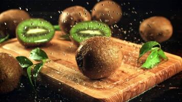 On the kiwi water droplets fall on the cutting board. On a black background. Filmed is slow motion 1000 frames per second. video