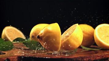 The lemon falls on the table and splits into two halves. On a black background. Filmed is slow motion 1000 fps. video