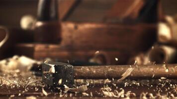 un martillo caídas en un mesa con de madera serrín. en un de madera antecedentes. filmado es lento movimiento 1000 marcos por segundo. video