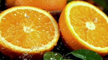 A Valencia orange and a Clementine are placed on a table, with water splashing on them. The citrus fruits belong to the Orange plant family video