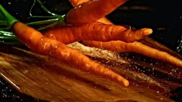 Super slow motion fresh carrots fall on the table. High quality FullHD footage video