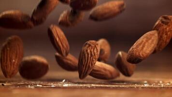 Almendras, un natural ingrediente, son cascada sobre un de madera mesa. esta de cerca, macro fotografía vitrinas el nueces en su caparazón, retratar un todavía vida de natural comidas video