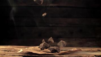 super lent mouvement chute pièces de amer, foncé Chocolat sur une en bois tableau. filmé sur une haute vitesse caméra à 1000 ips. video