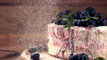 Super schleppend Bewegung pulverisiert Zucker Stürze auf das Blaubeere Kuchen. auf ein hölzern Hintergrund. gefilmt auf ein schnelle Geschwindigkeit Kamera beim 1000 fps. video