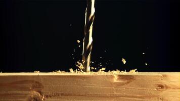 The drill drills wood with sawdust. On a black background. Filmed is slow motion 1000 fps. video